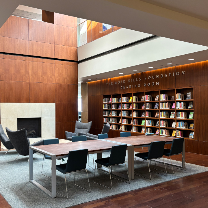 large wooden table with book shelf and fireplace in background